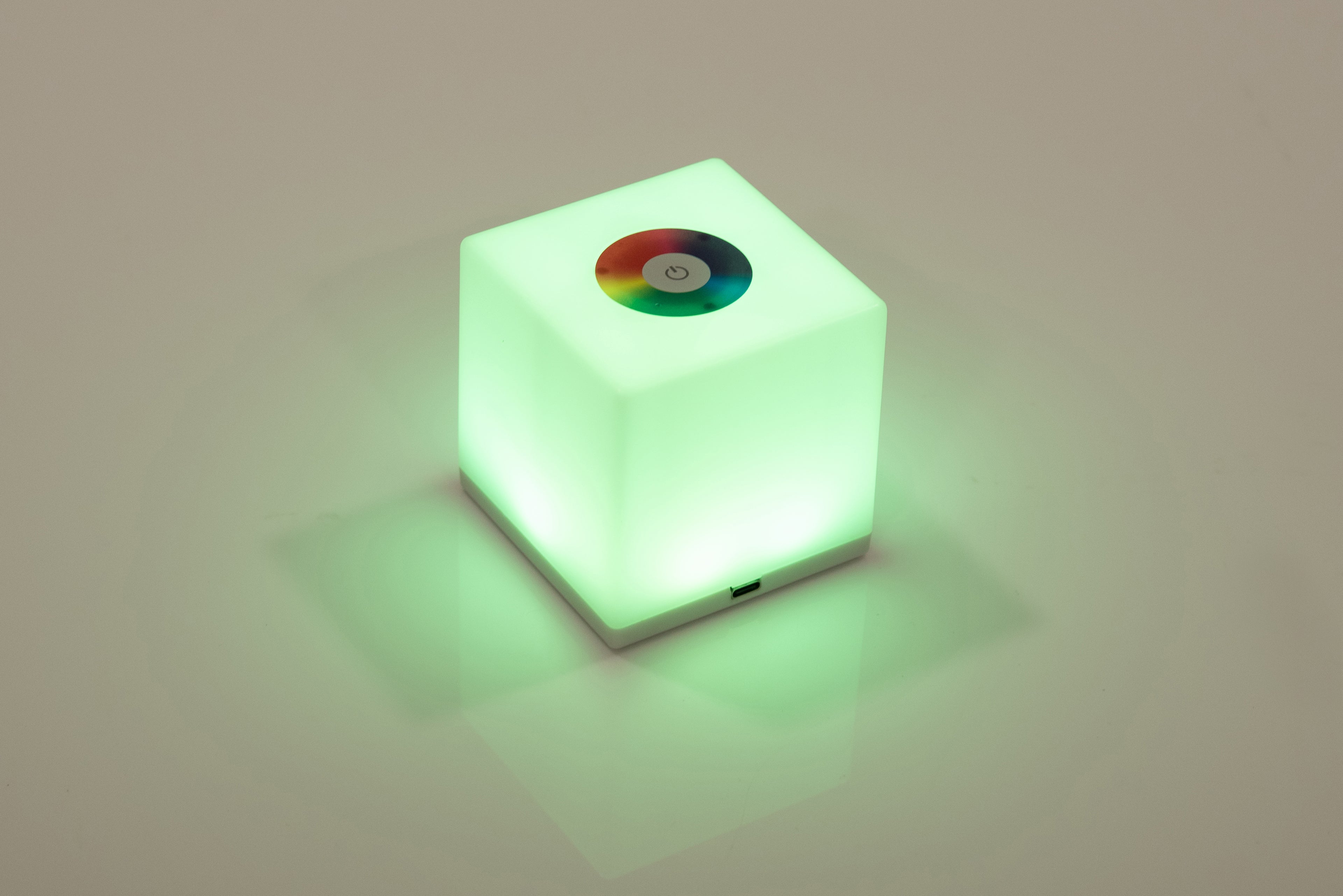 Mini cube LED lamp glowing green with circular top lens