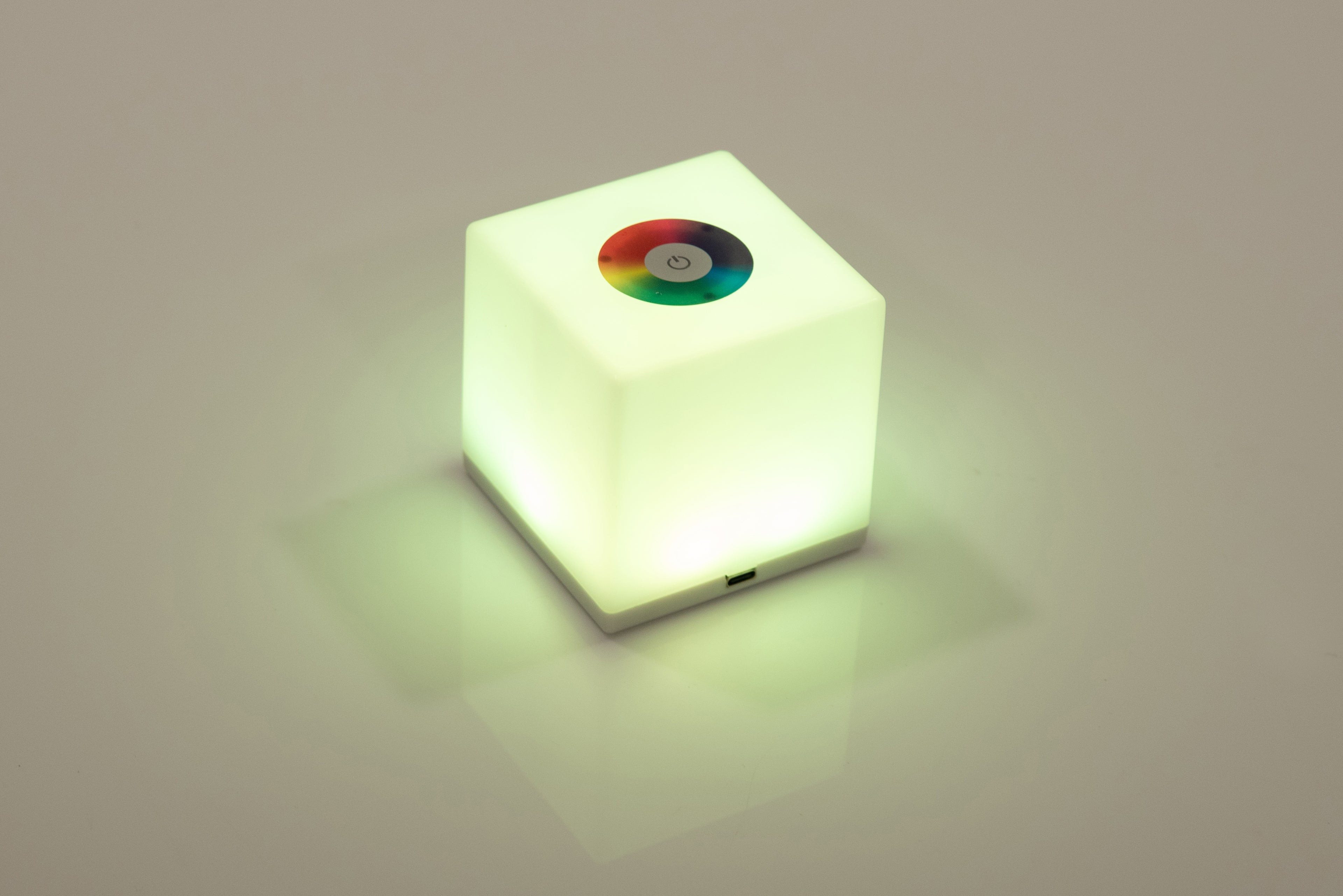 Mini cube LED lamp glowing green with circular top lens