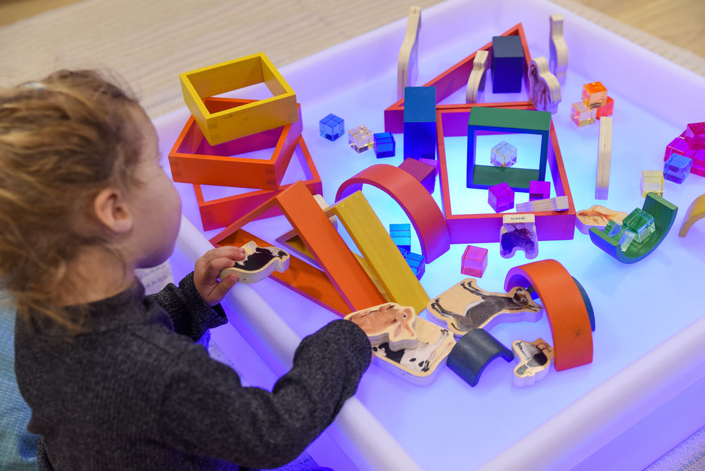 Square glow play table with purple-lit white tray and building blocks