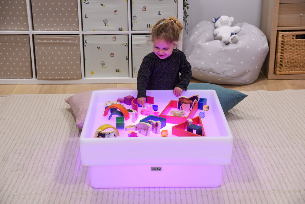Square glow play table with purple-lit tray and colorful toy set