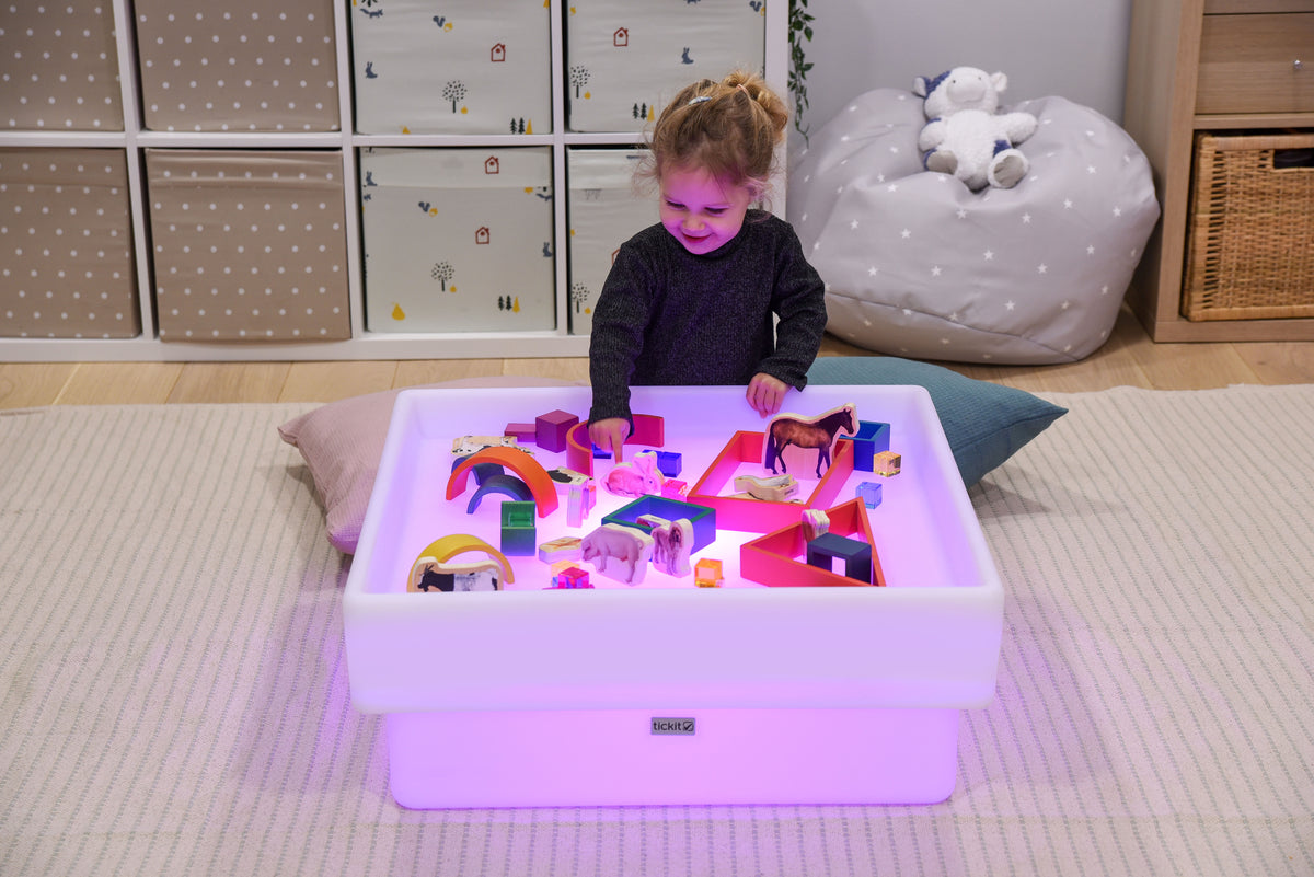 Square glow play table with purple-lit tray and colorful toy set
