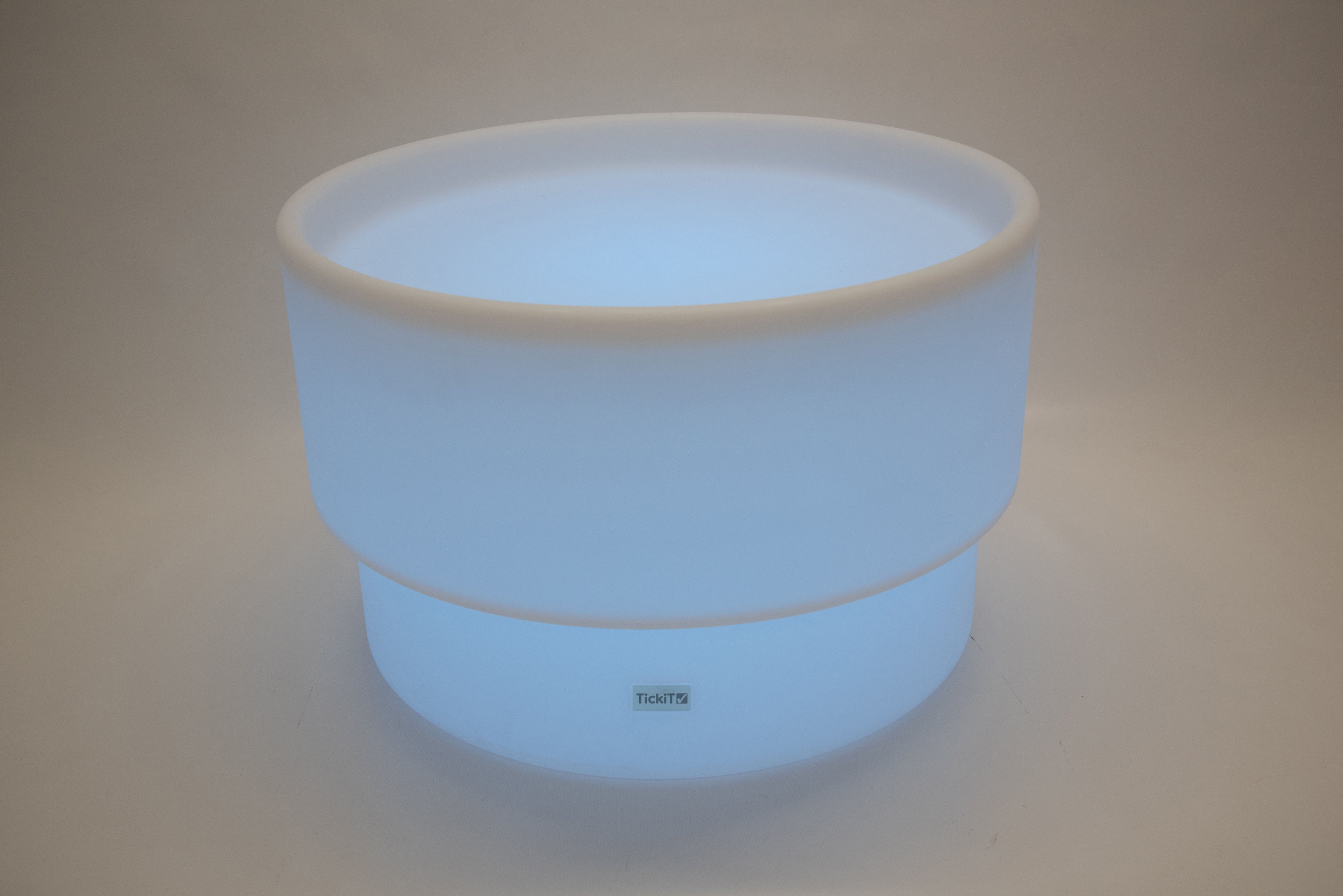 Round tabletop light, light blue glow with white rim and smooth cylindrical shape