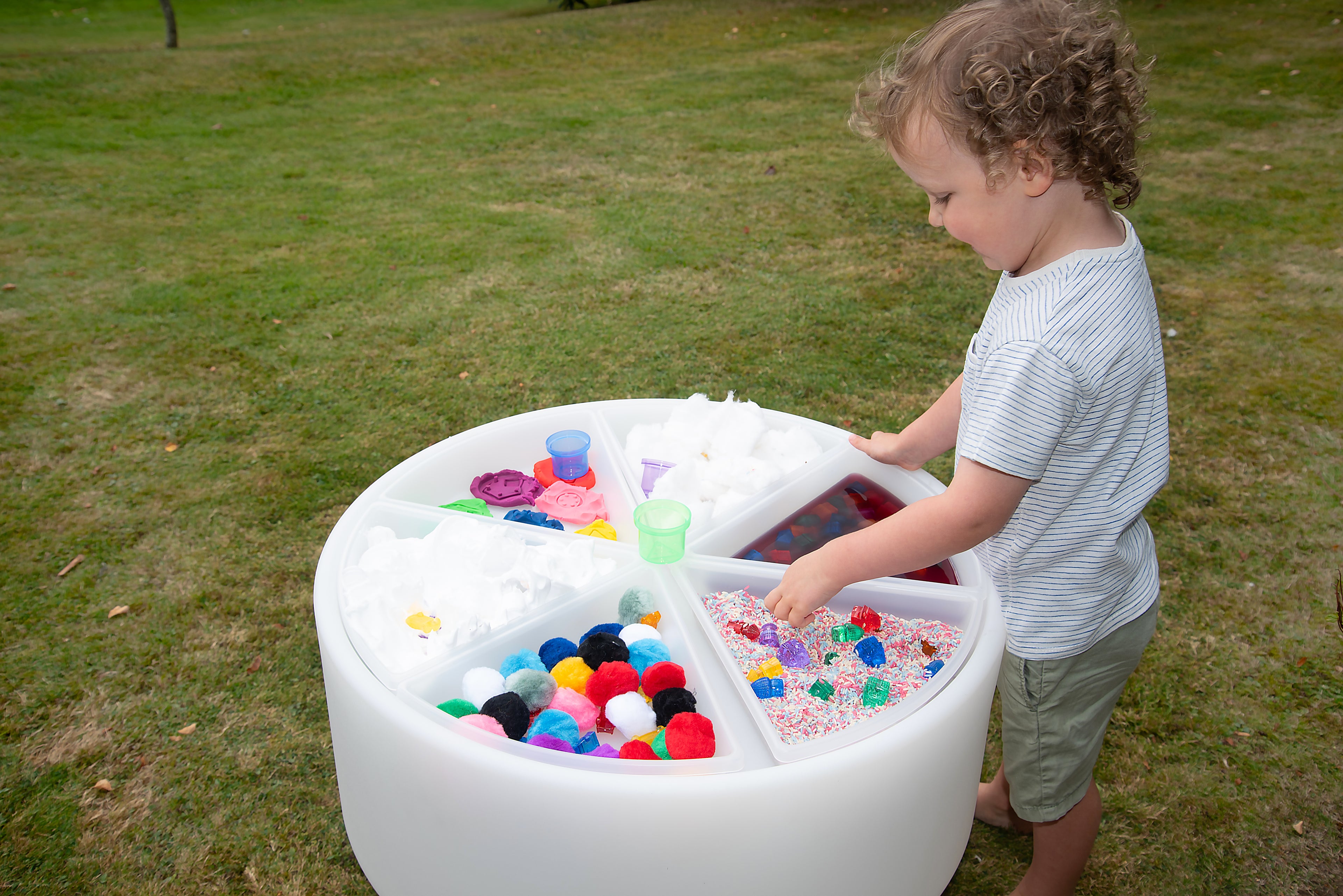 Round glow table with colorful beads on top, used outdoors by a child