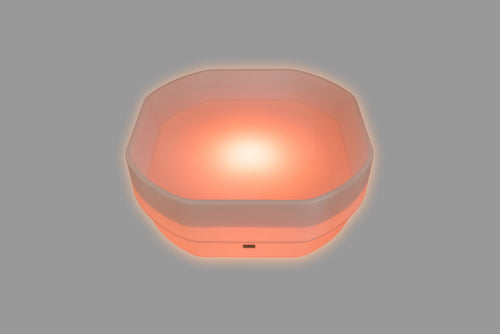 Hexagonal LED glow table with pink-orange light and translucent sides