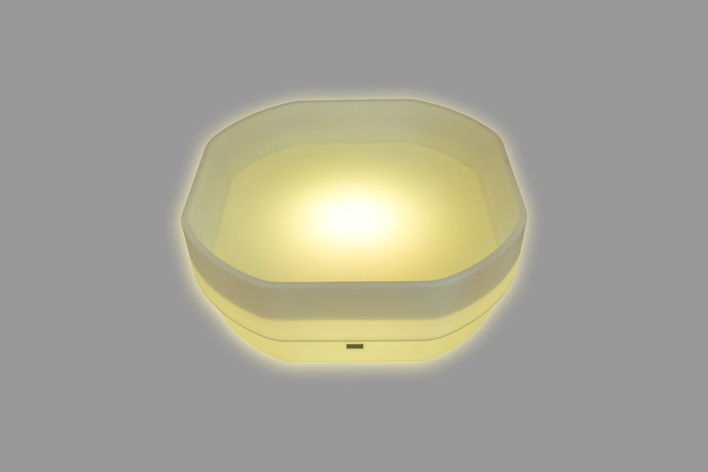 Hexagonal LED glow table with warm yellow light and translucent sides
