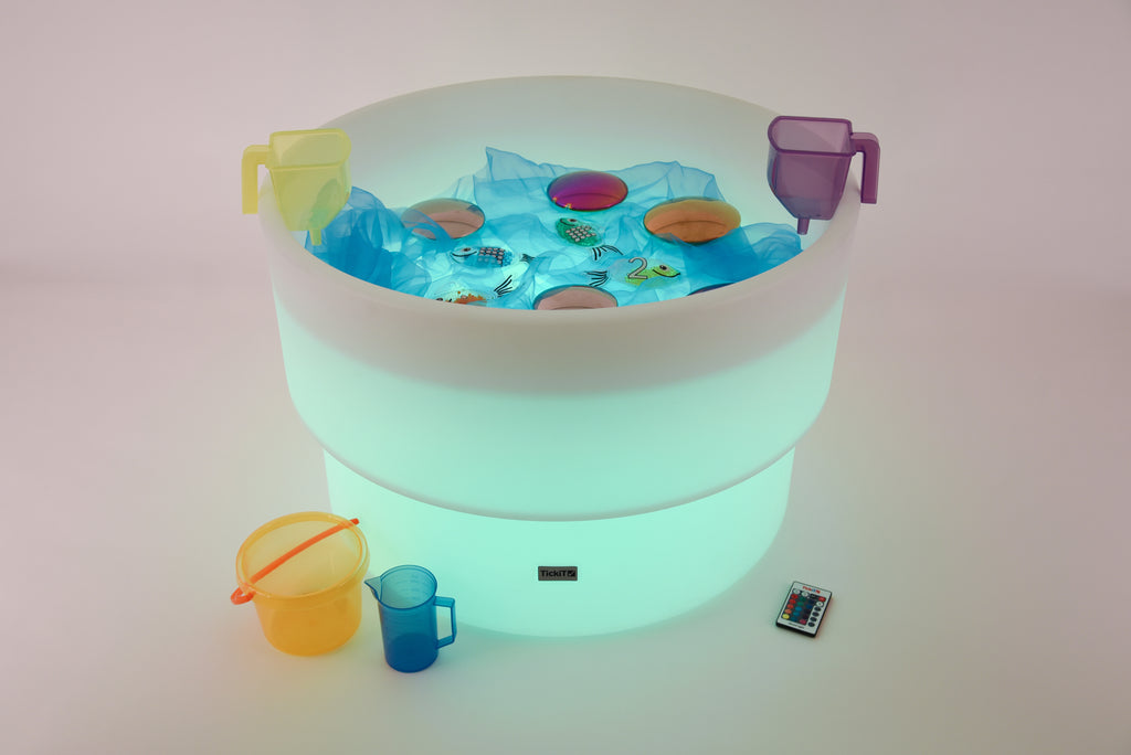 Glowing water table with floating toy pieces and blue cup accessories