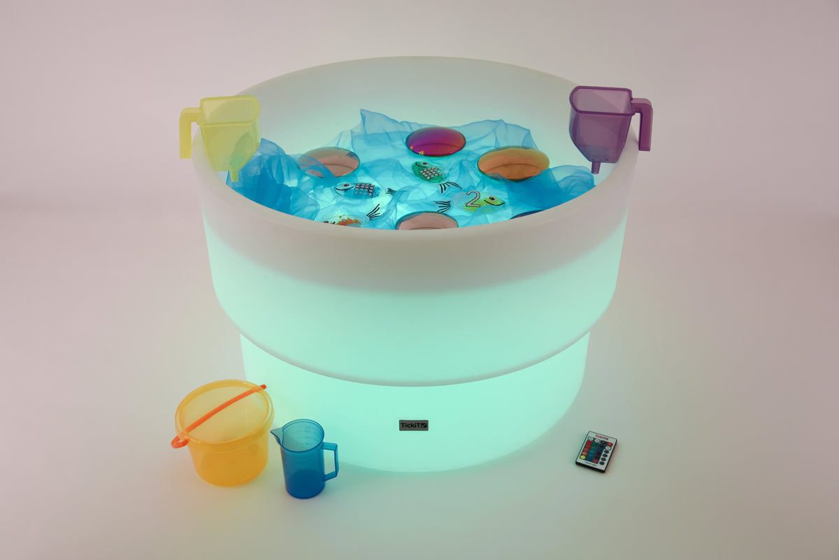 Glowing water table with floating toy pieces and blue cup accessories