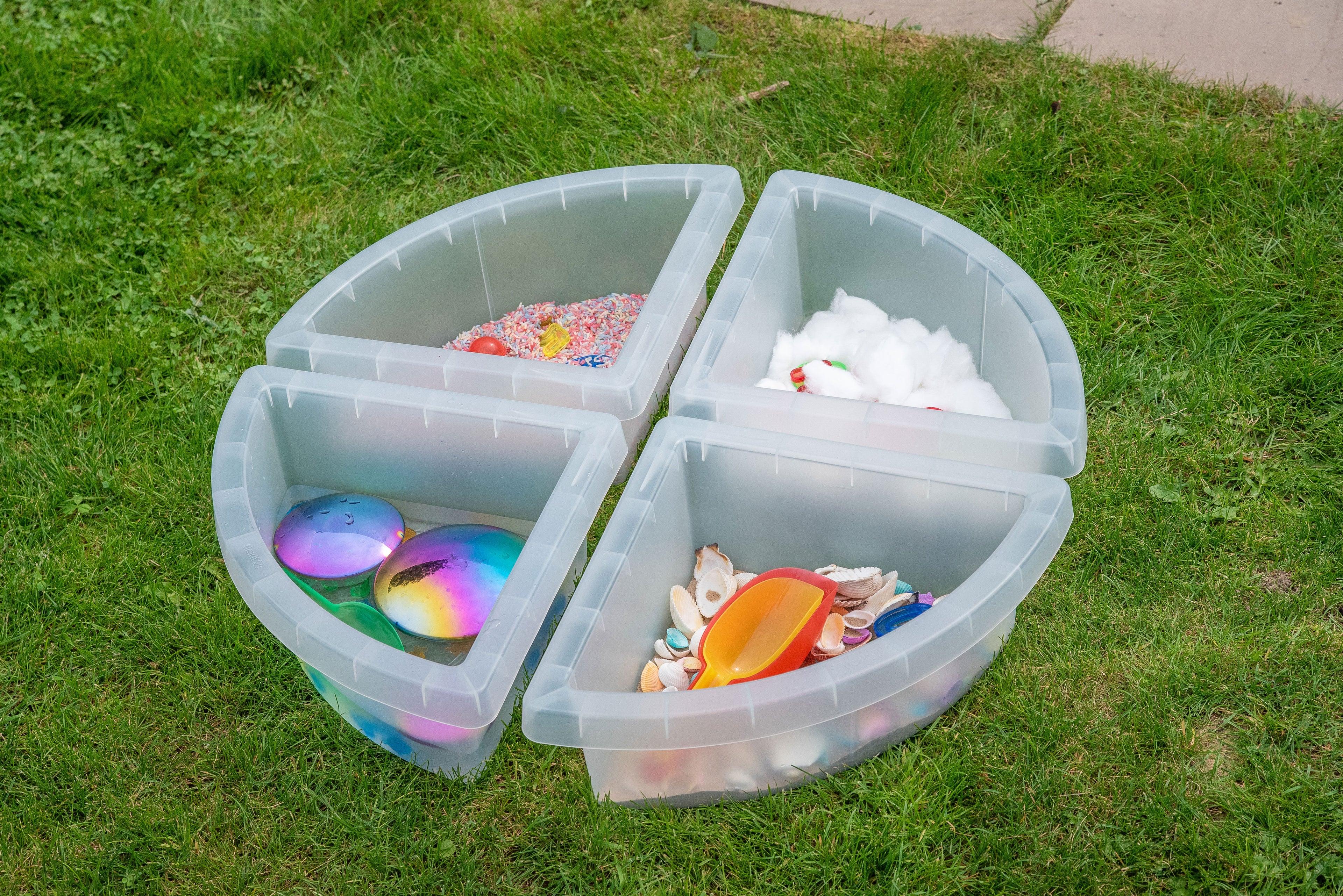 Round clear quadrant tray with four sections, holding assorted colorful sensory items