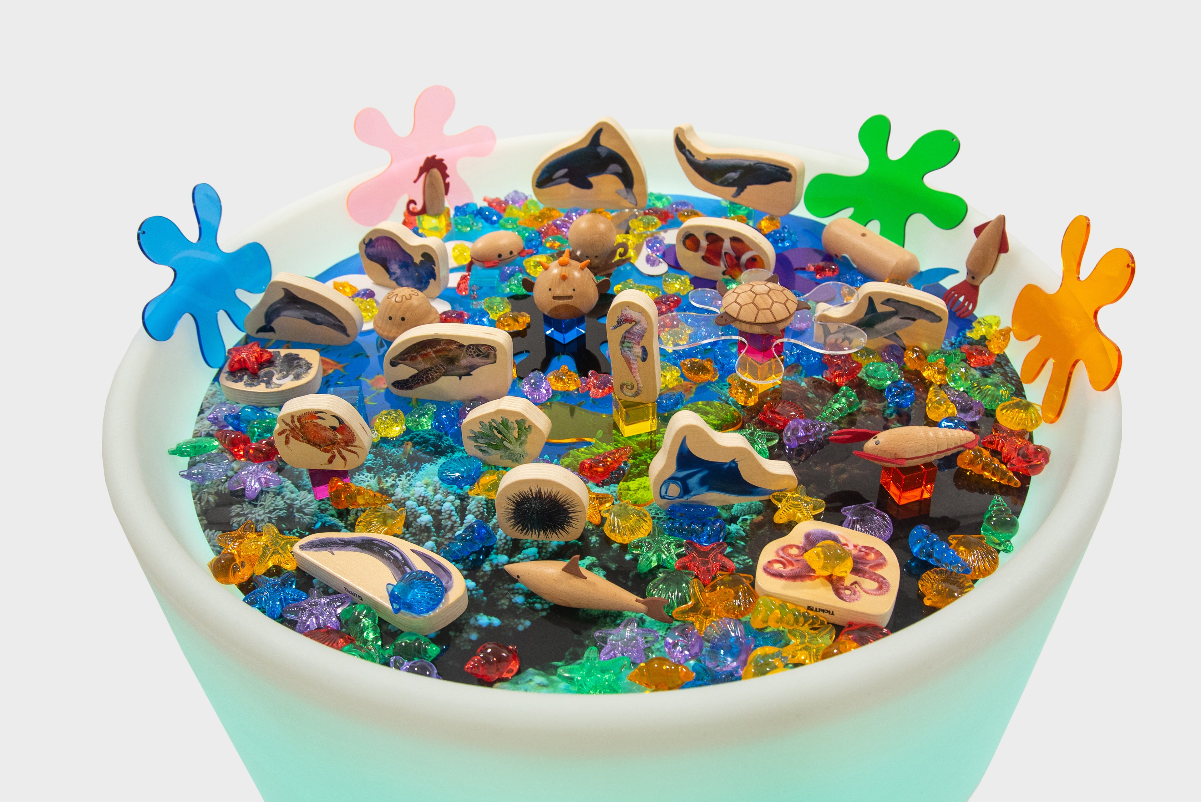 Round sea-themed table with colorful ocean animal toys, shells, and coral