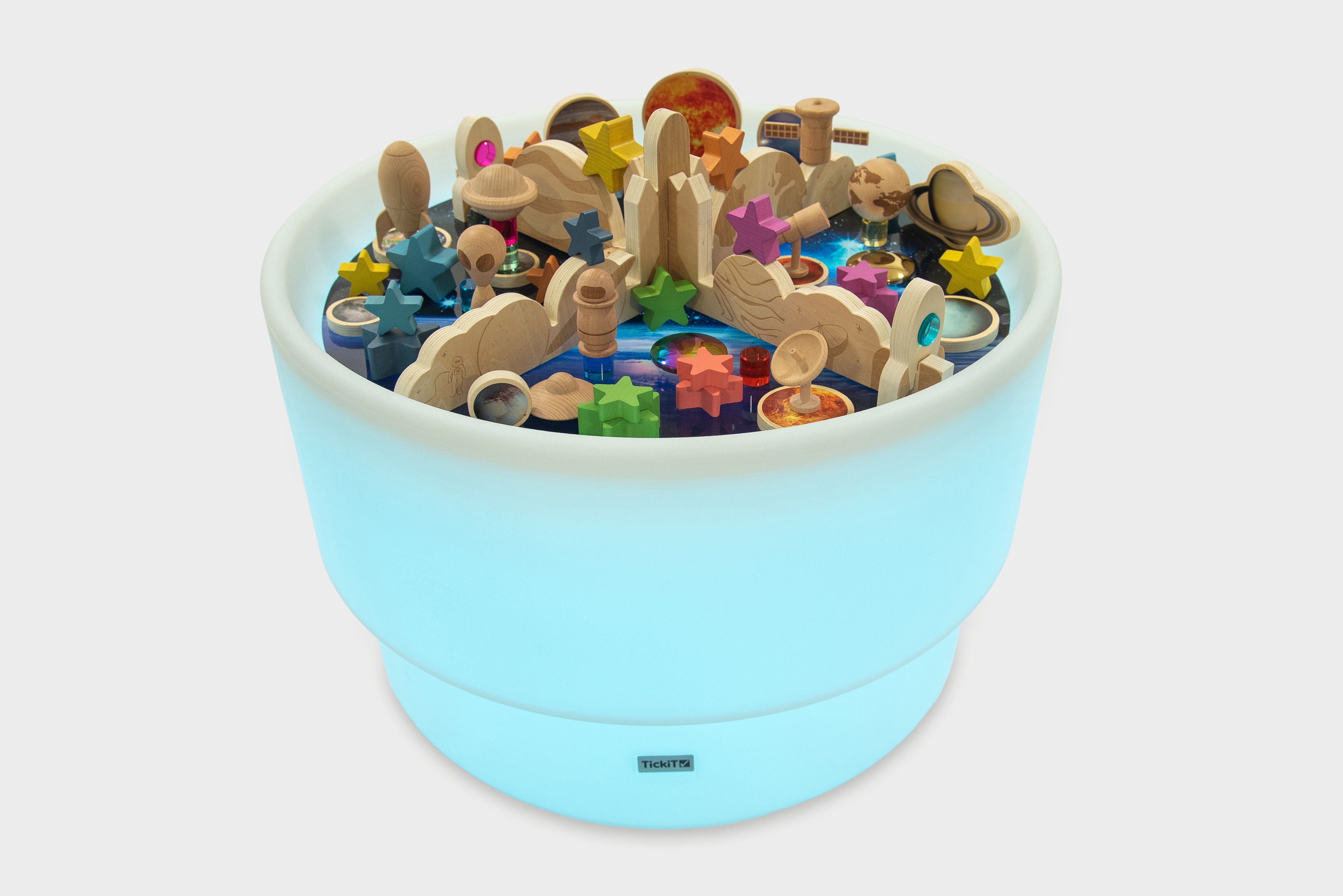 Blue glowing space play table filled with wooden planets, stars, and blocks