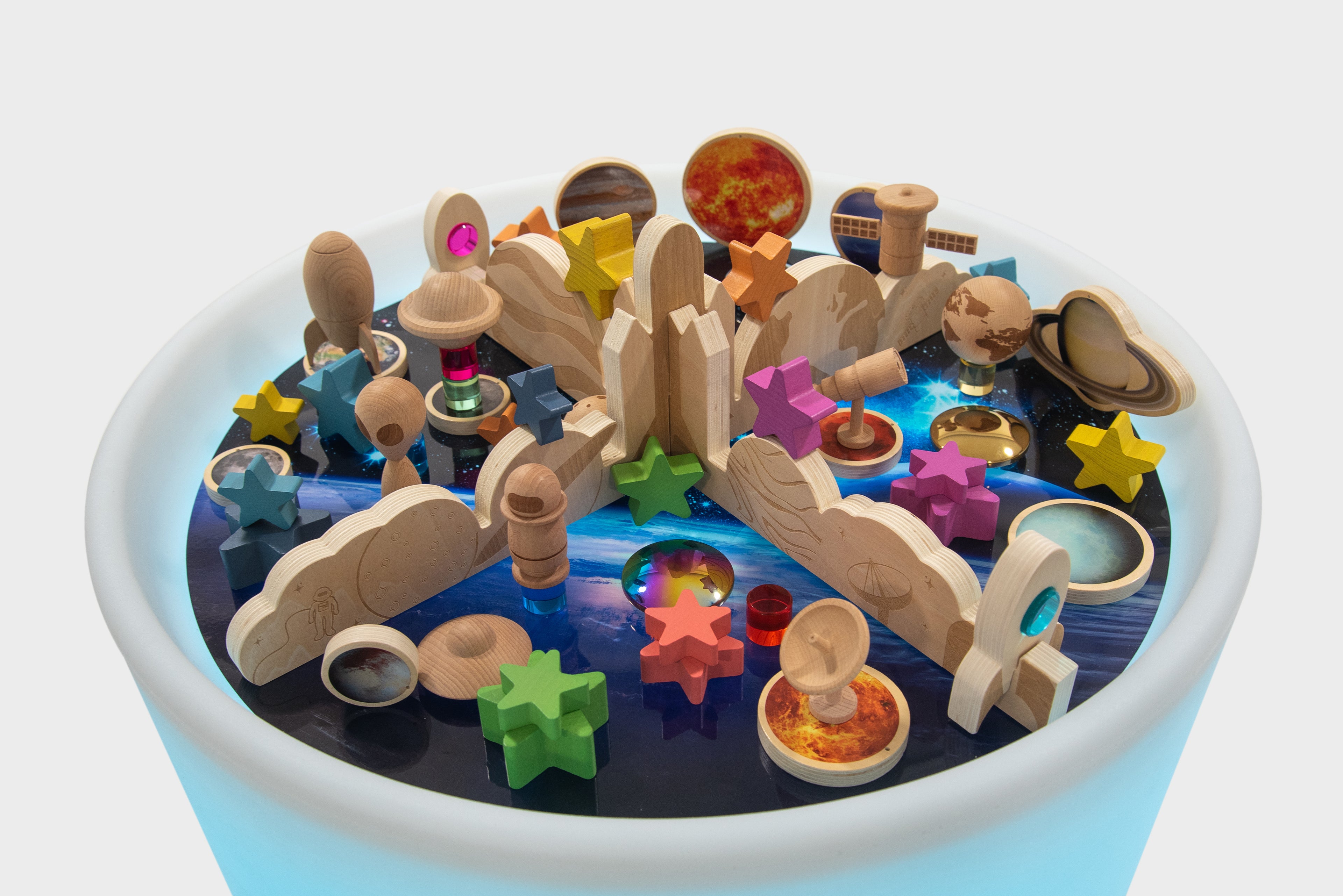Top view of glowing space play table with planets, stars, and wooden pieces