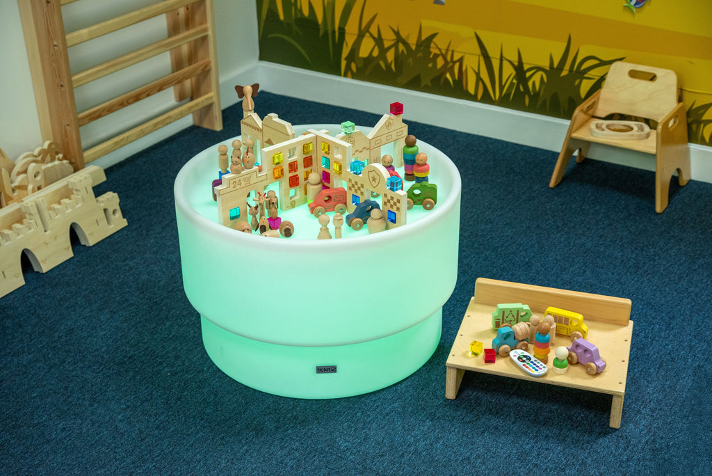 Round Discovery Town play table with miniature buildings, people figures, and toy pieces