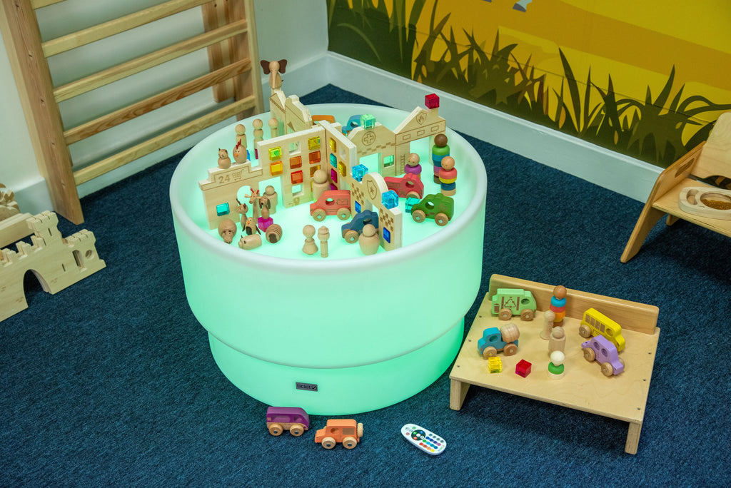 Discovery Town play table with miniature town set inside, with toy accessories nearby
