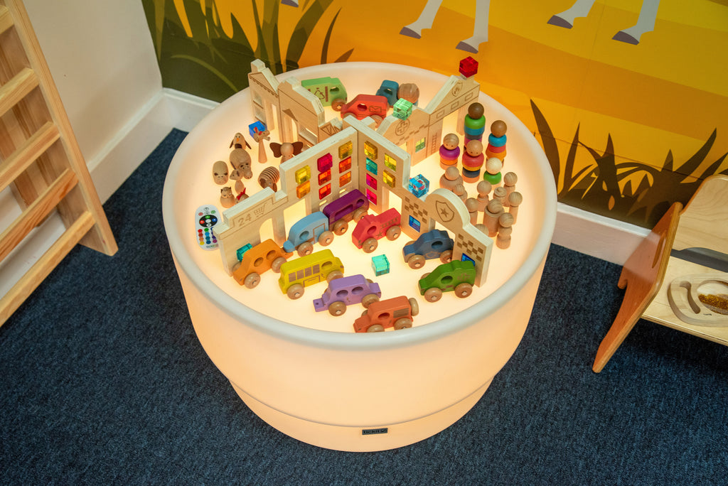 Kids discovery town table with colorful wooden toy pieces on round play surface