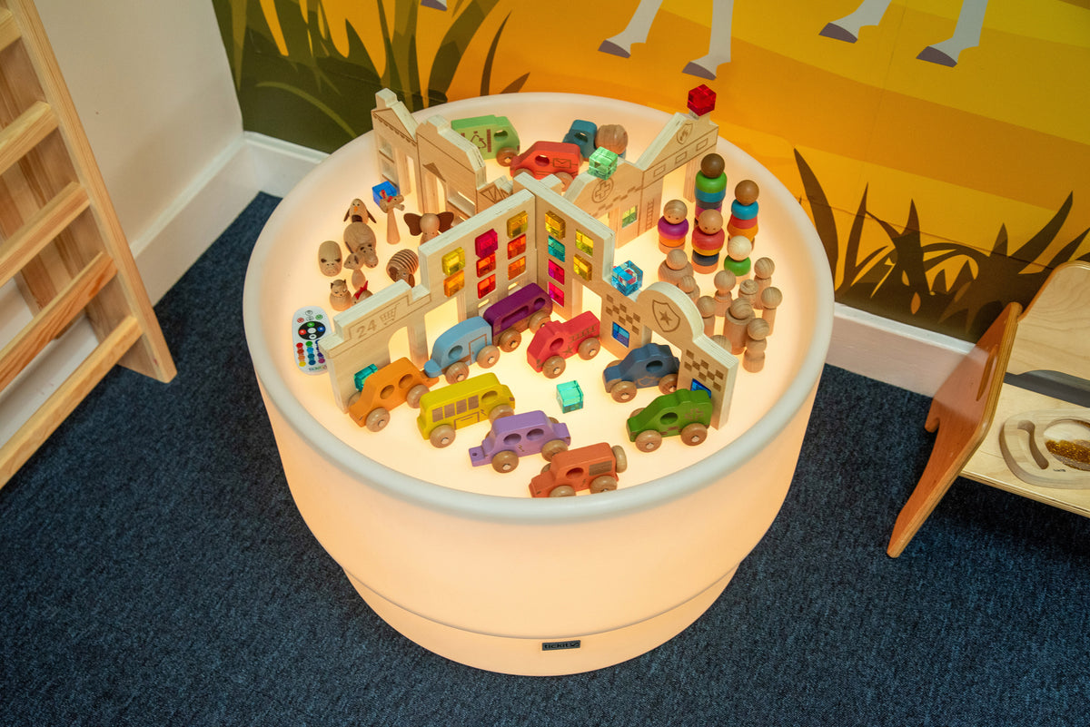 Kids discovery town table with colorful wooden toy pieces on round play surface