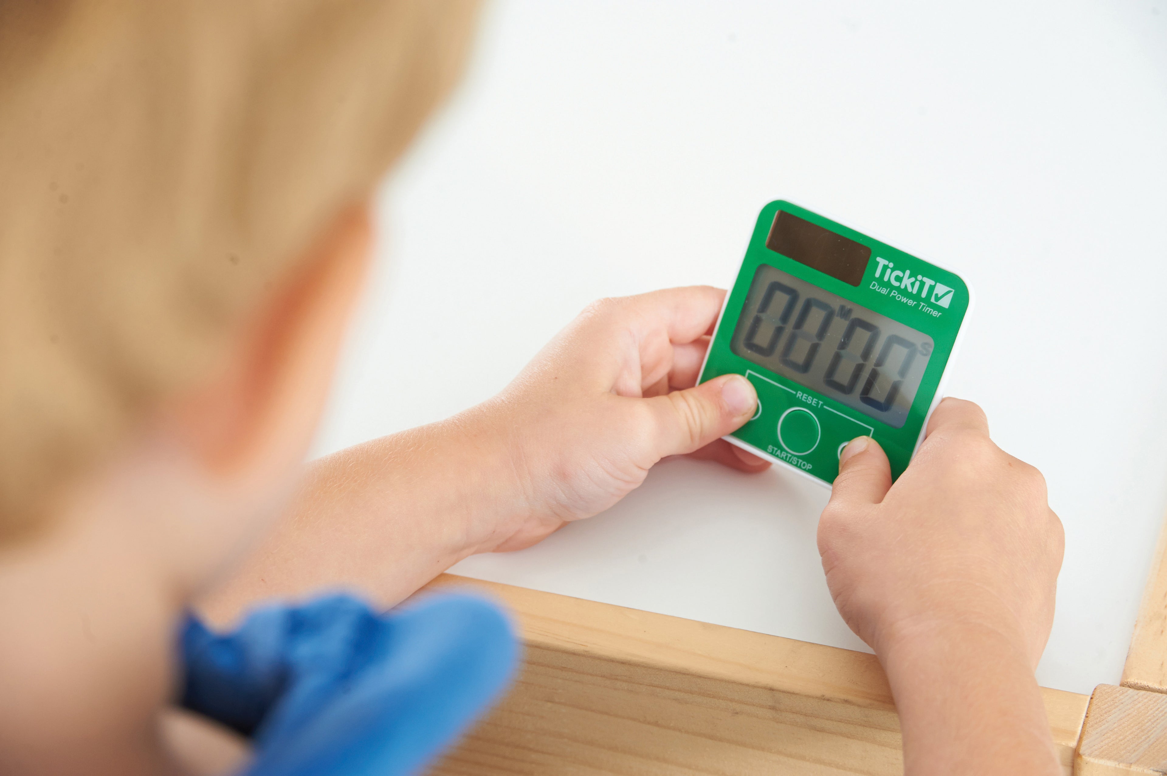 Green dual power digital timer held in hand, with LCD display and three buttons.