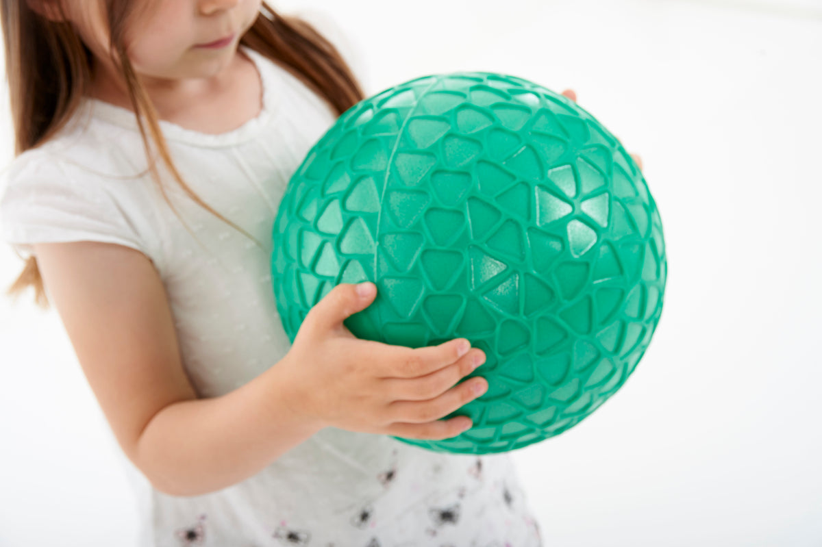 Green textured grip ball with bumpy pattern held by a child