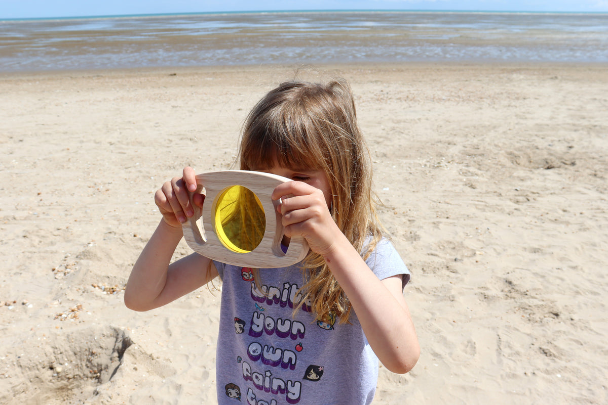 Wooden color panel frame with translucent yellow window held by a child outdoors