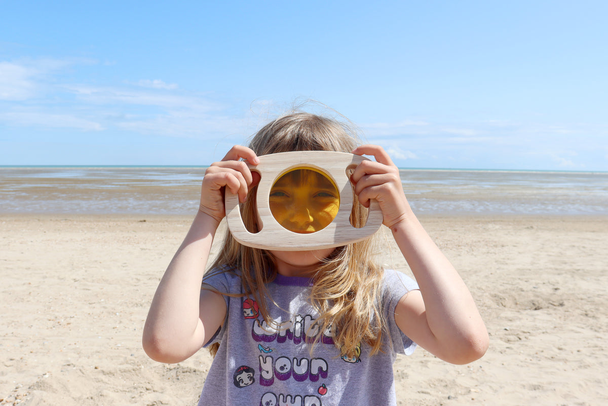 Child holding a wooden sensory face visor with an amber tinted viewing window