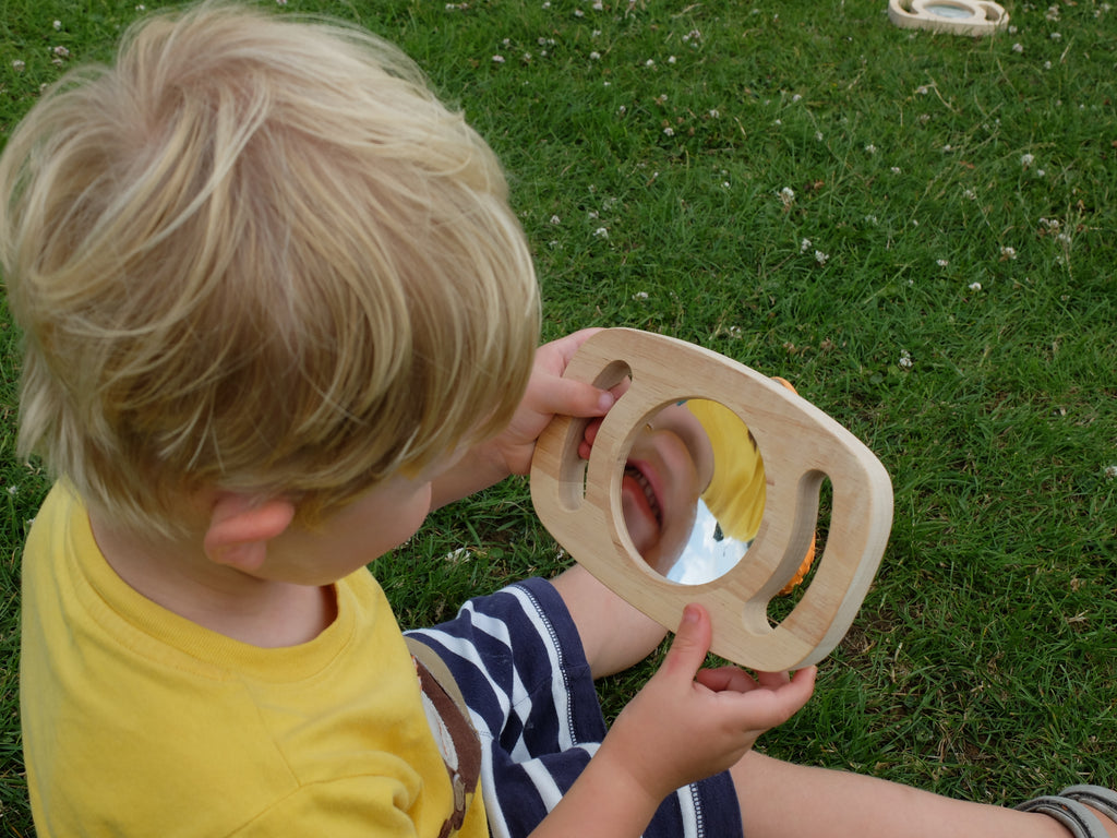Light wood oval double-sided convex/concave mirror toy held by a child