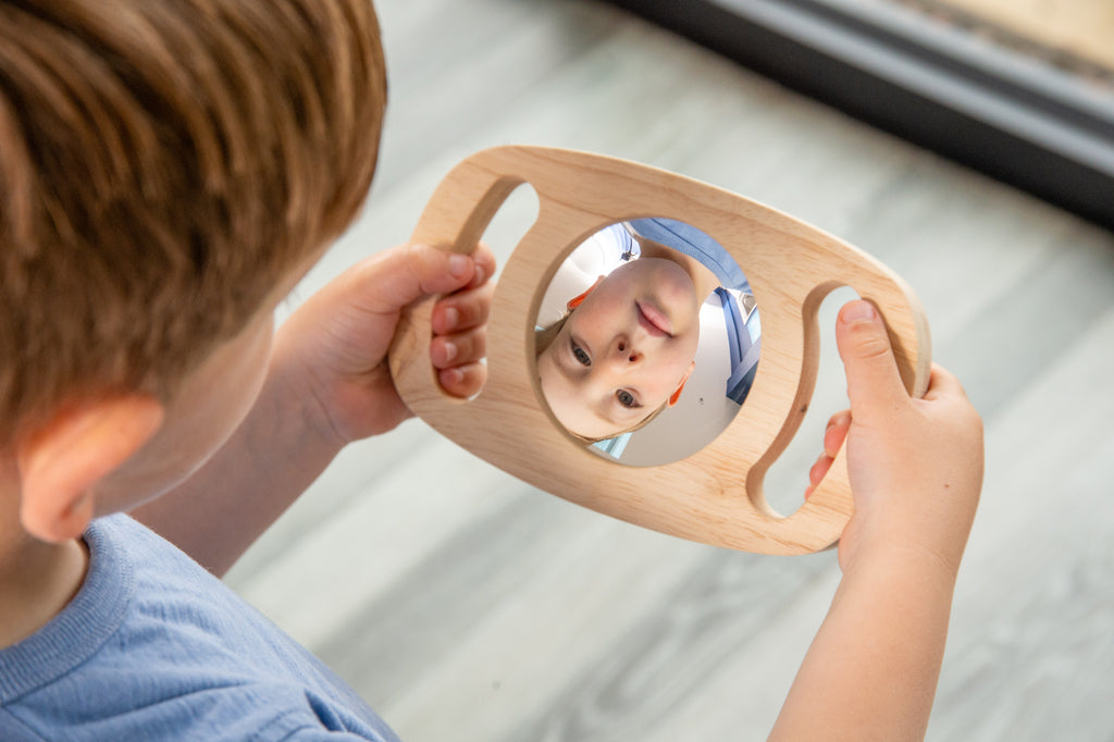 Light wood double-sided oval mirror toy showing a child reflection