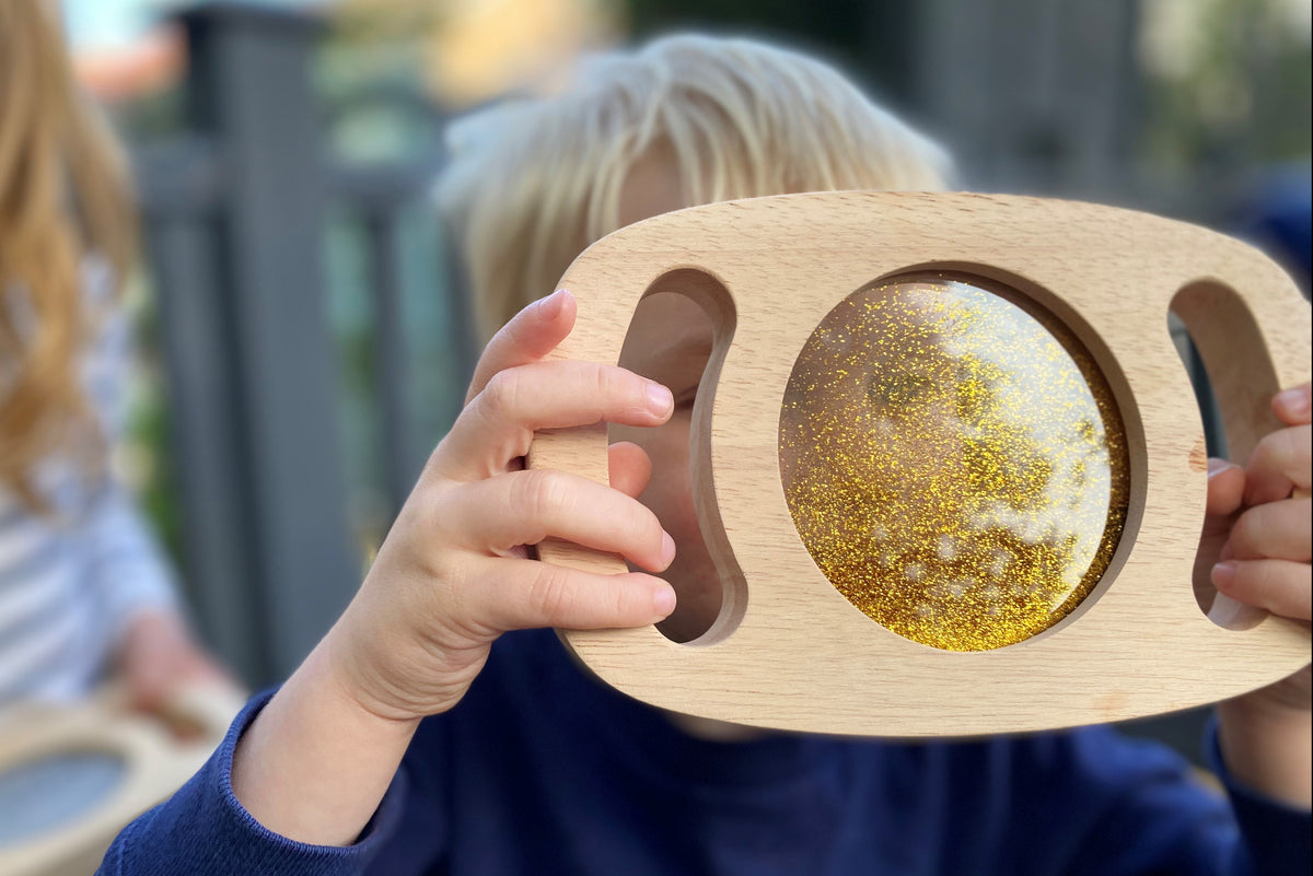 Gold glitter circle panel on light wood frame with hand cutouts