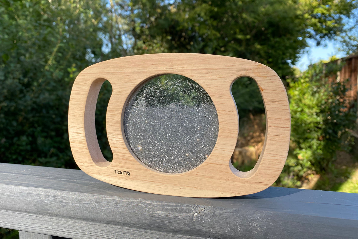 Silver glitter circle panel on light wood frame with hand cutouts