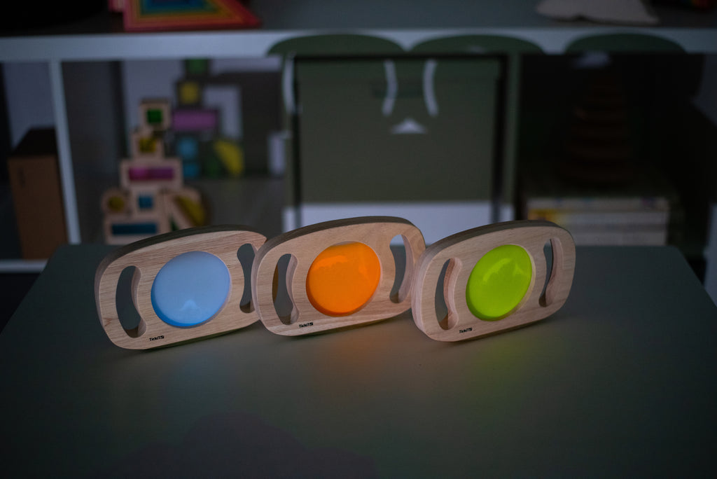Three wooden glow panels with blue, orange, and lime green illuminated discs
