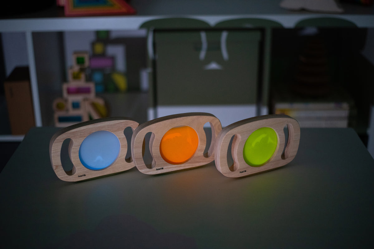 Three wooden glow panels with blue, orange, and lime green illuminated discs