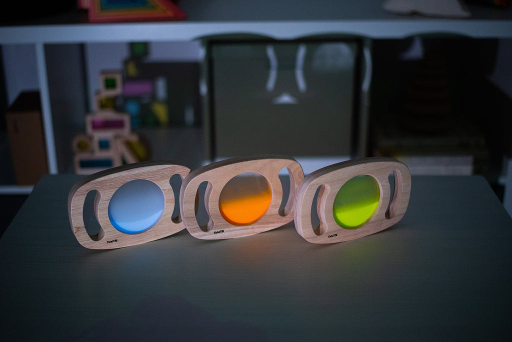 Three wooden glow panels with blue, orange, and green illuminated discs