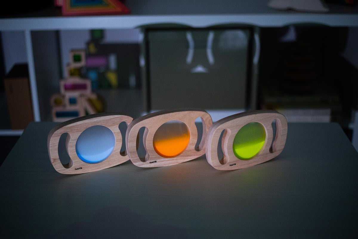 Three wooden glow panels with blue, orange, and green illuminated discs