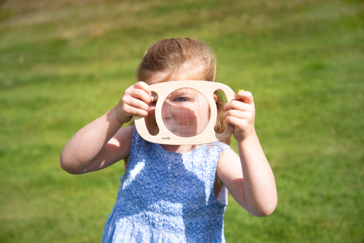 White kaleidoscope toy with circular blue viewing lens, held up by a child