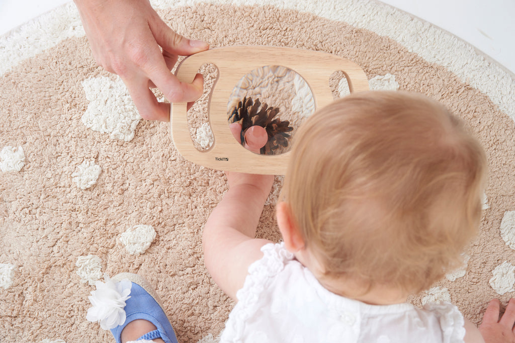 Wooden handheld magnifier with large round lens, held by a child
