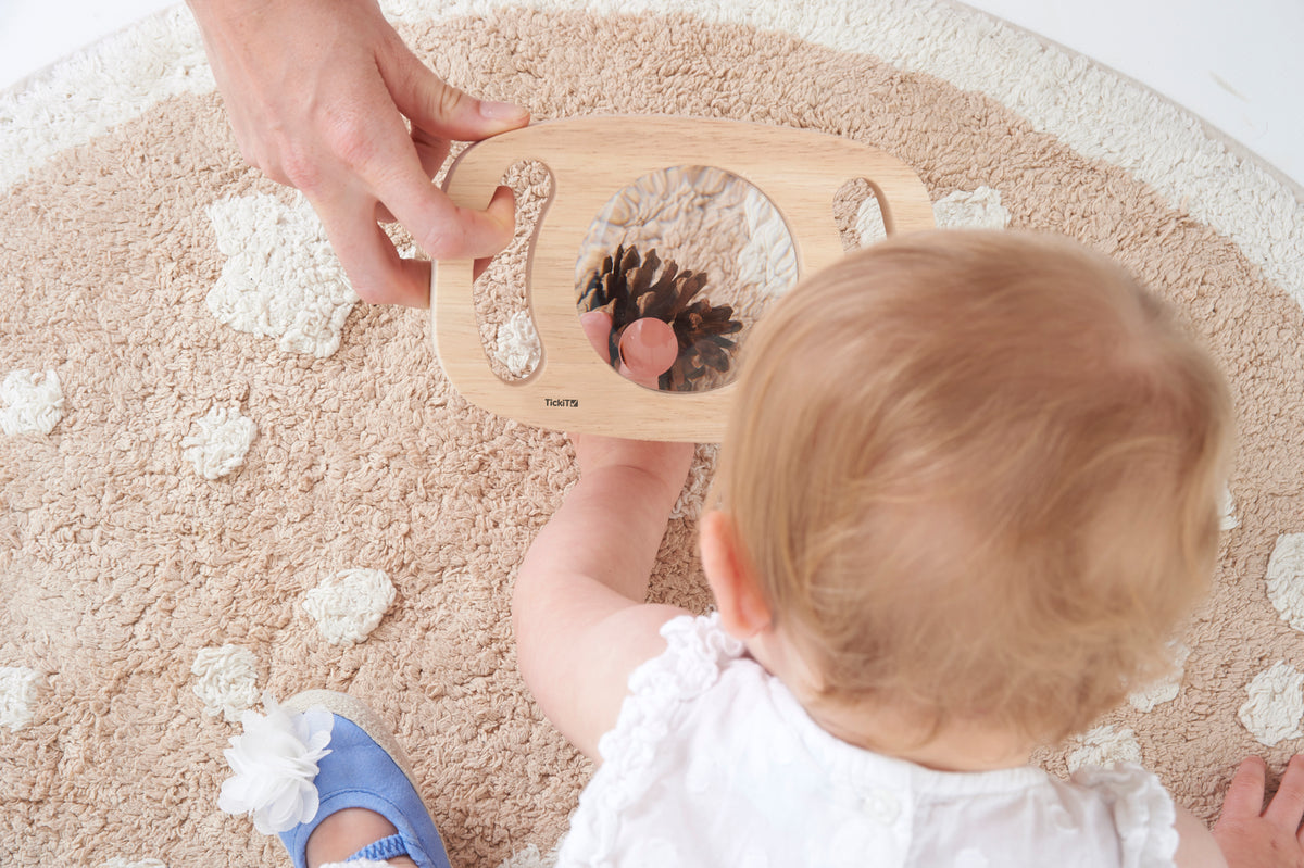 Wooden handheld magnifier with large round lens, held by a child