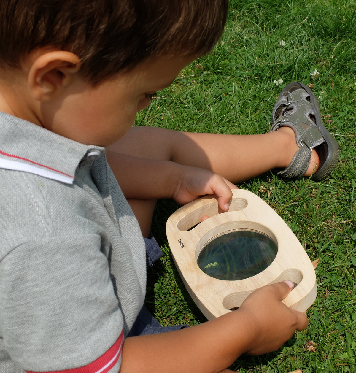 Handheld wooden magnifier with round glass lens, child holding it