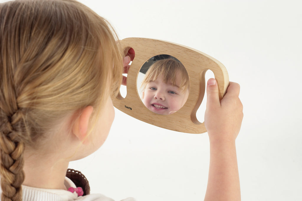 Oval wooden frame mirror for toddlers, reflecting a smiling child