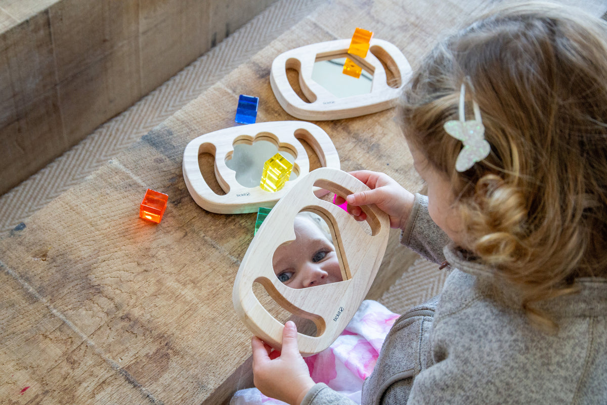 Wooden shape mirror frames with colorful pieces; toddler hands reaching on floor