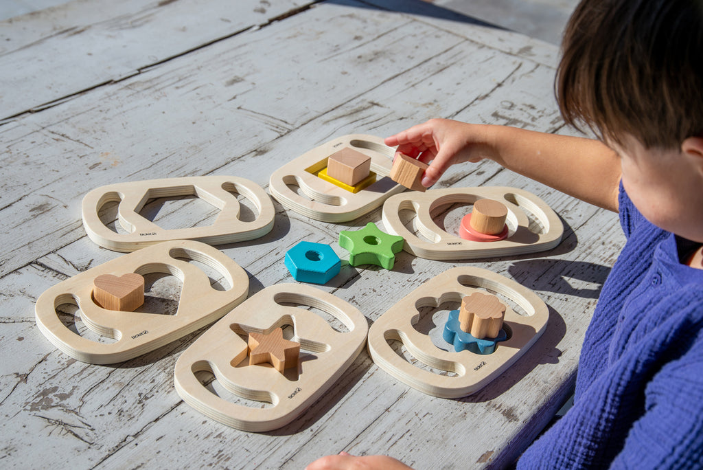 Wooden shape sorter tray with colorful wooden blocks and star, circle, flower pieces