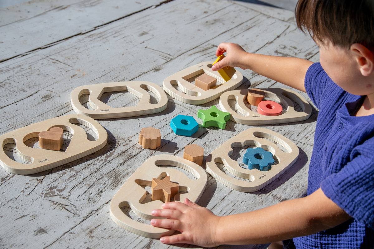 Wooden shape sorter with curved base boards and colorful wooden pieces on floor