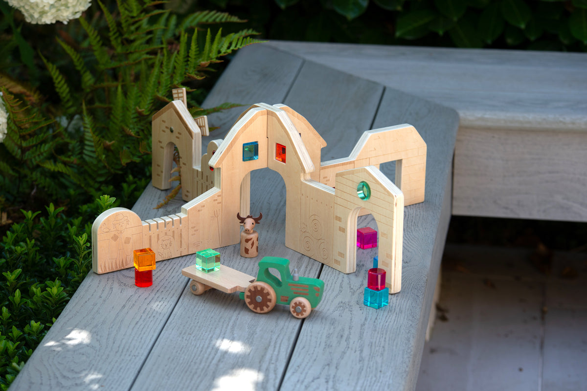 Wooden farm play dividers on outdoor table with small figures, cart, and colorful blocks
