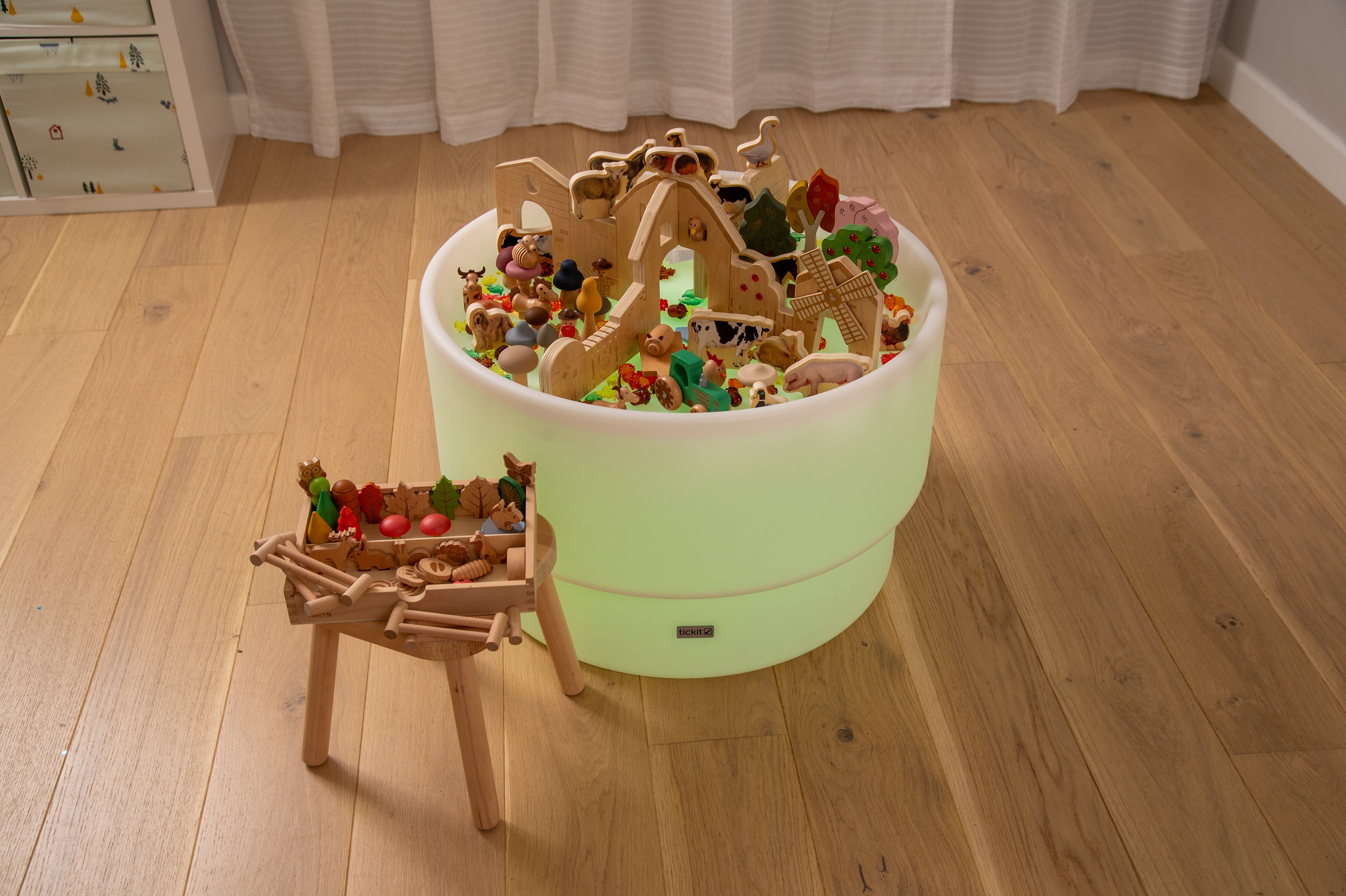 Wooden farm resource toy bundle in a round bucket beside a small wooden table.