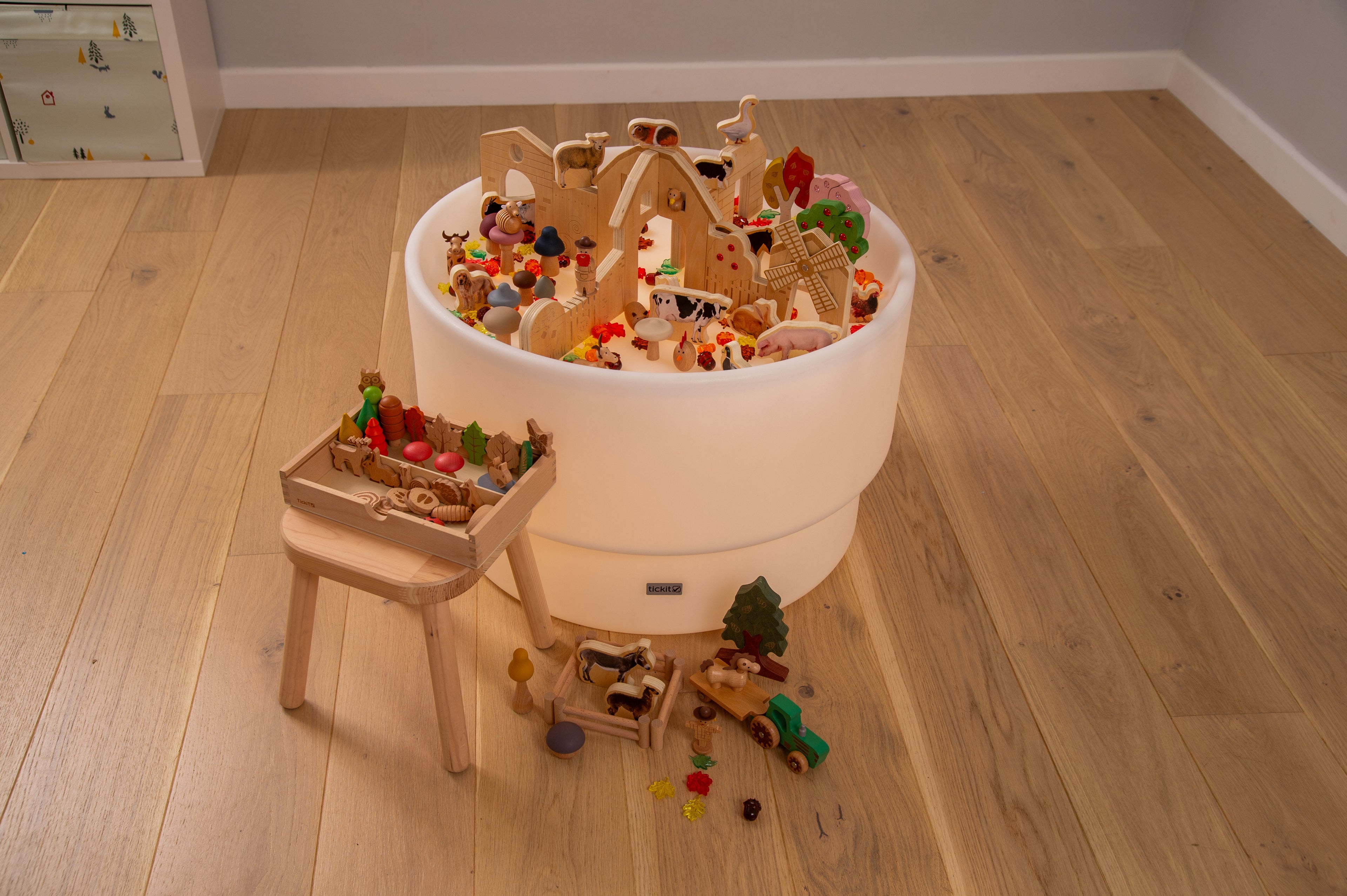 Wooden farm resource toy bundle spilling from a round bucket with a small wooden table.