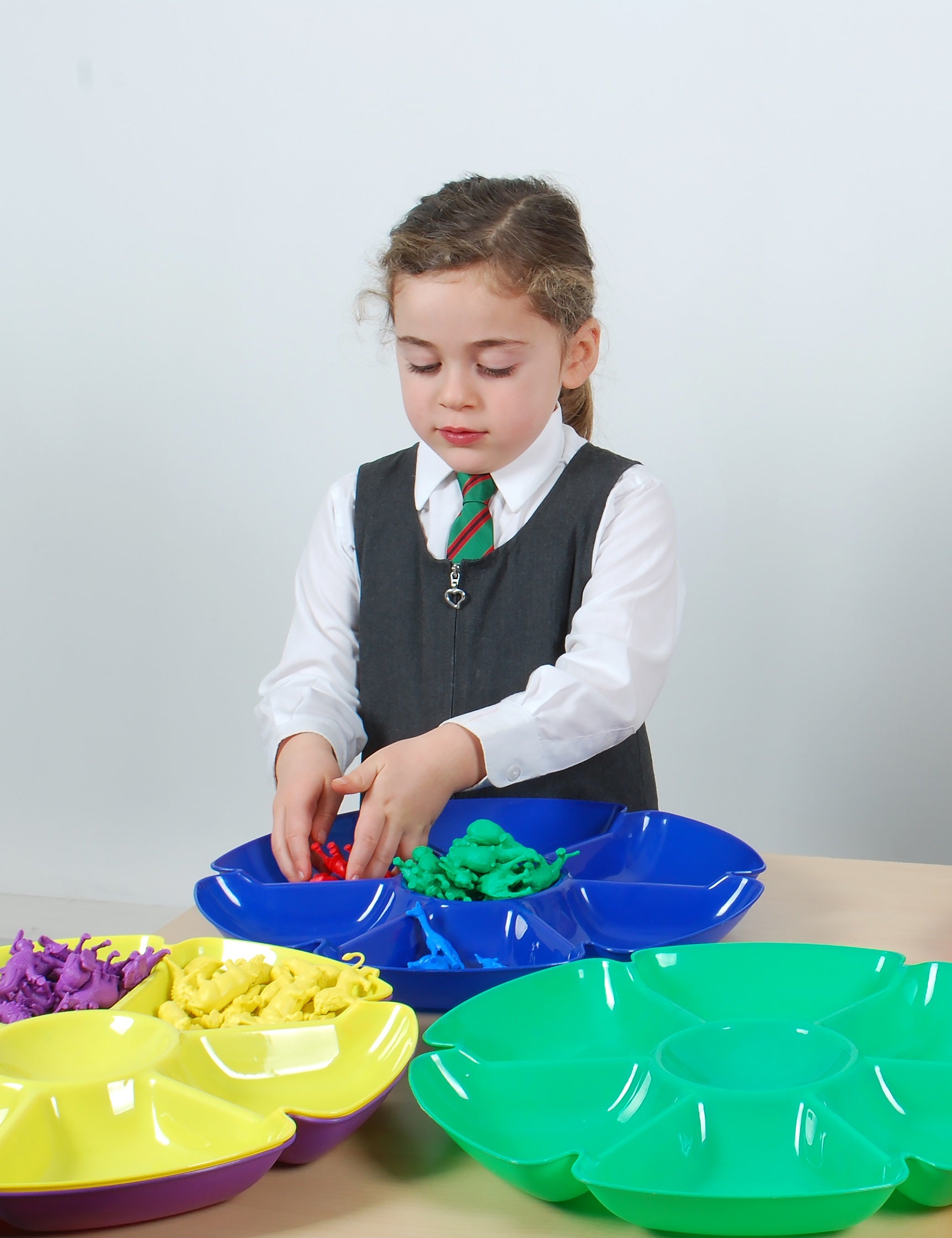 Six flower-shaped paint trays in yellow, green, and blue with circular compartment sections