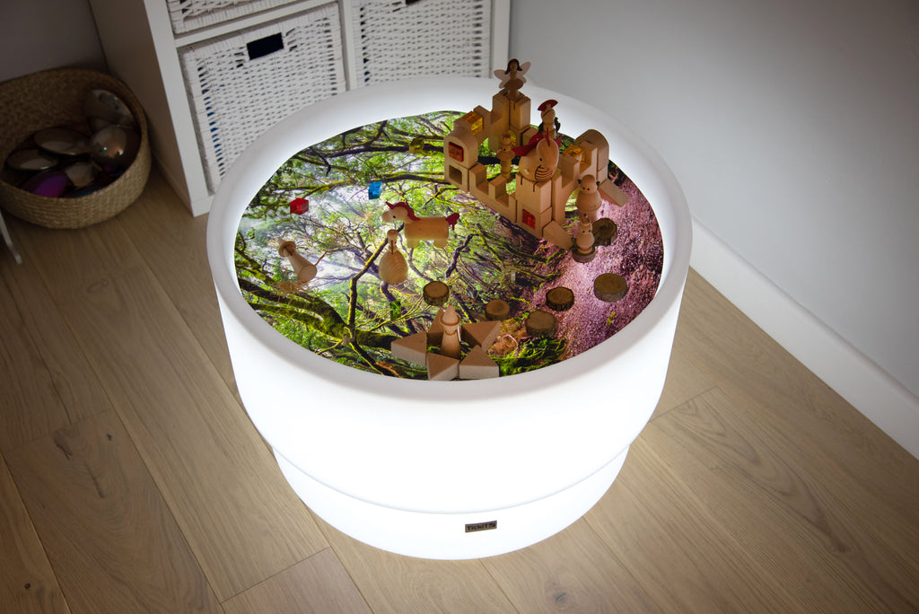 Round forest-themed play mat with forest scene insert and small toy buildings, top view
