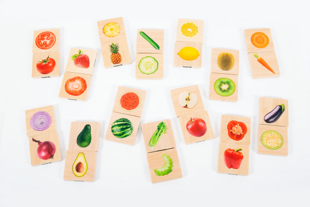 Assorted fruit and vegetable matching cards spread out on a tabletop