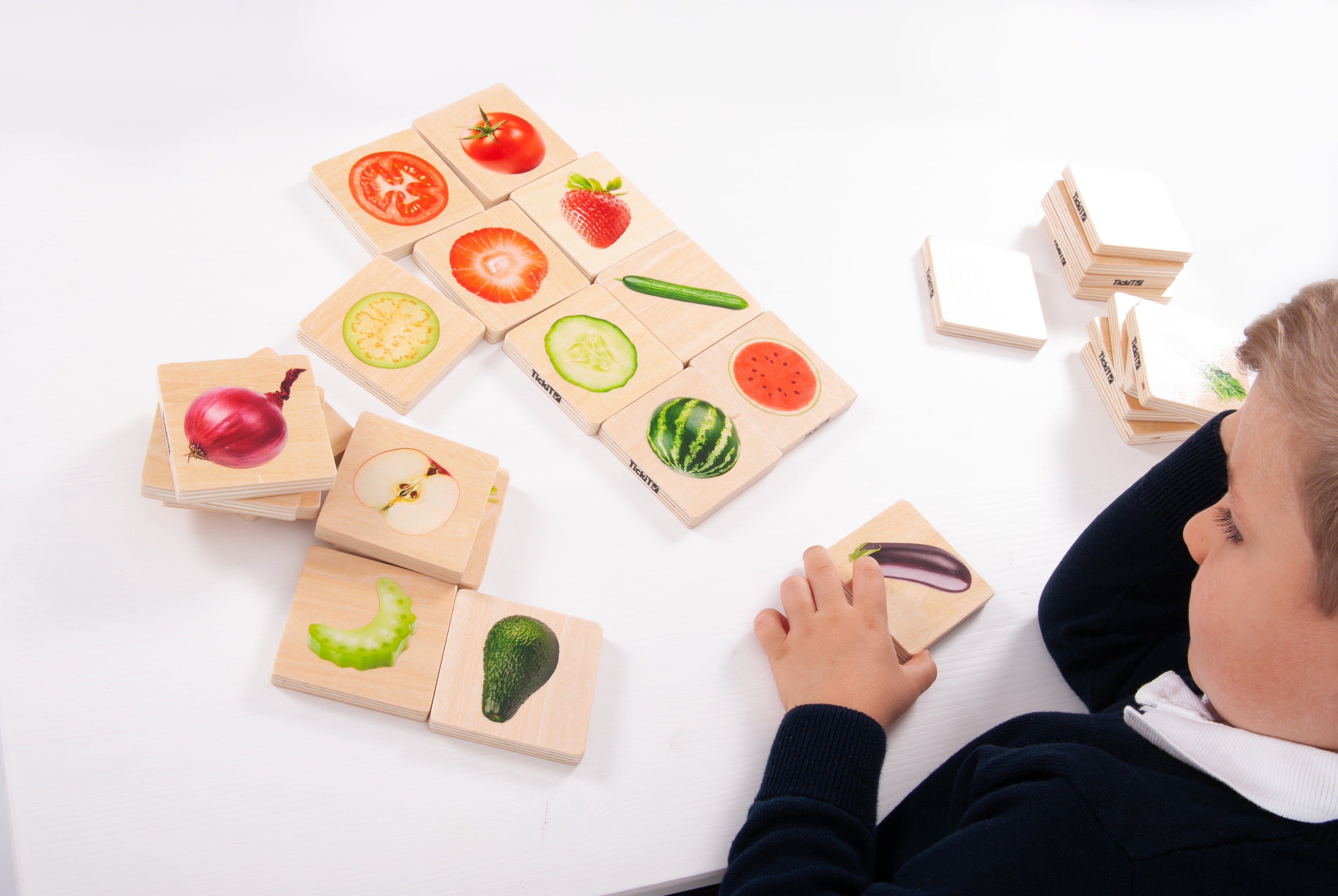 Fruit and vegetable picture cards with a child arranging matching tiles