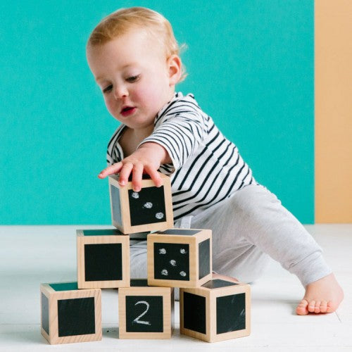 Stack of wooden chalkboard cubes with black faces and white numbers, including cube with '2'.