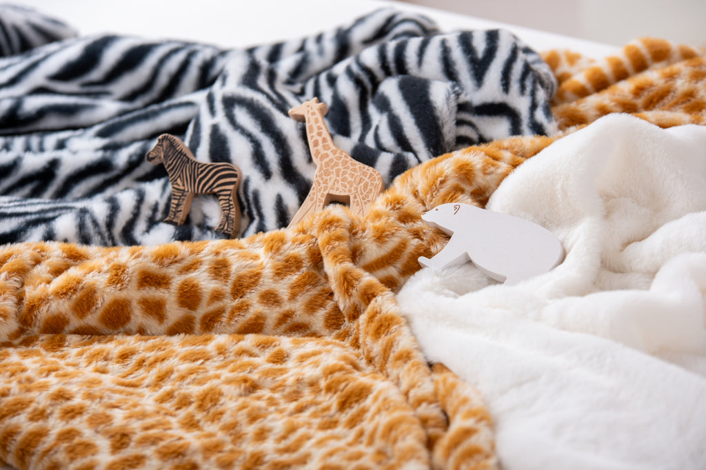 Close-up of animal print plush fabrics: black zebra, orange giraffe spots, white underside