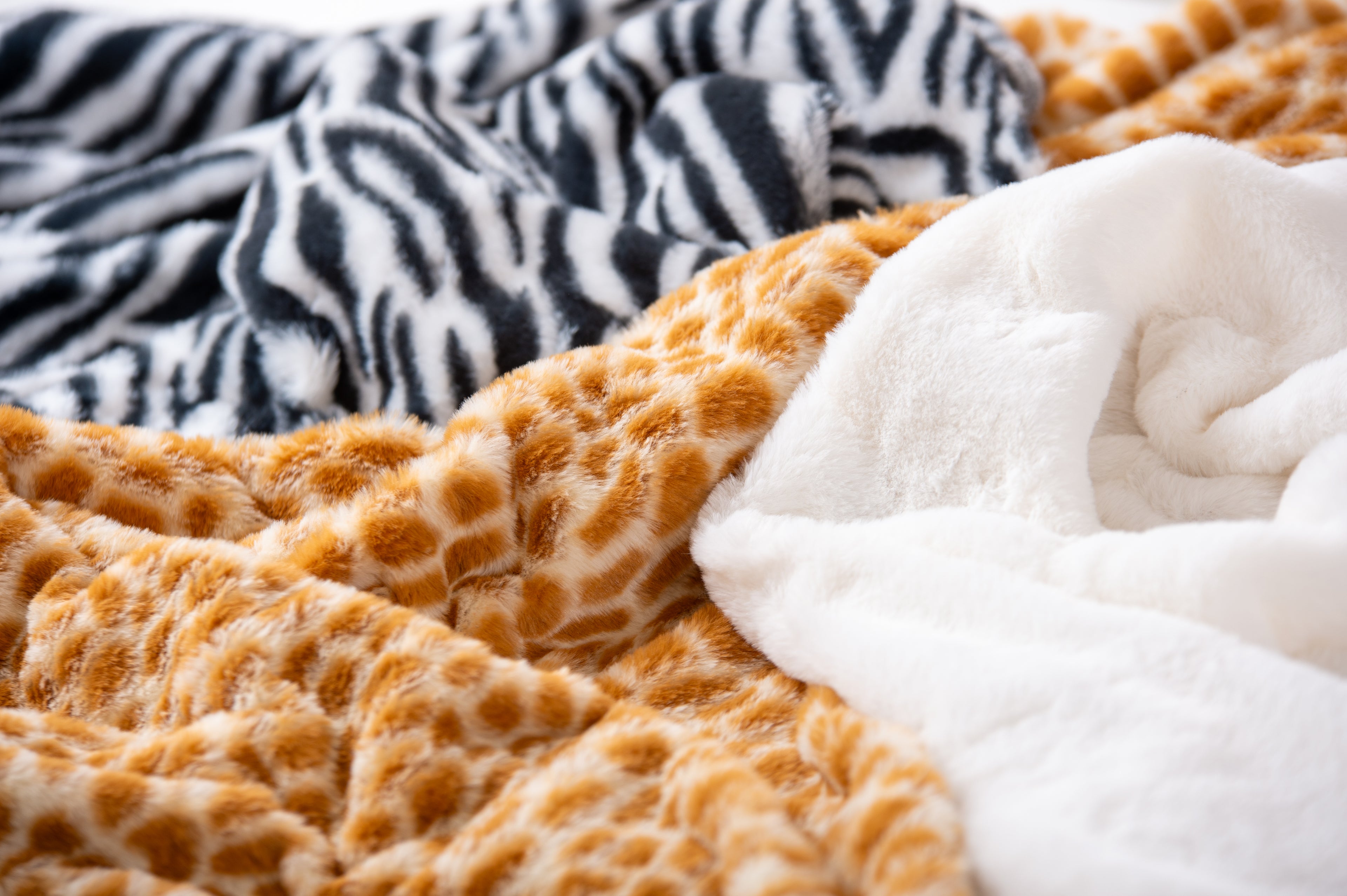 Close-up of furry fabric: black zebra stripes, orange giraffe spots, white plush backing