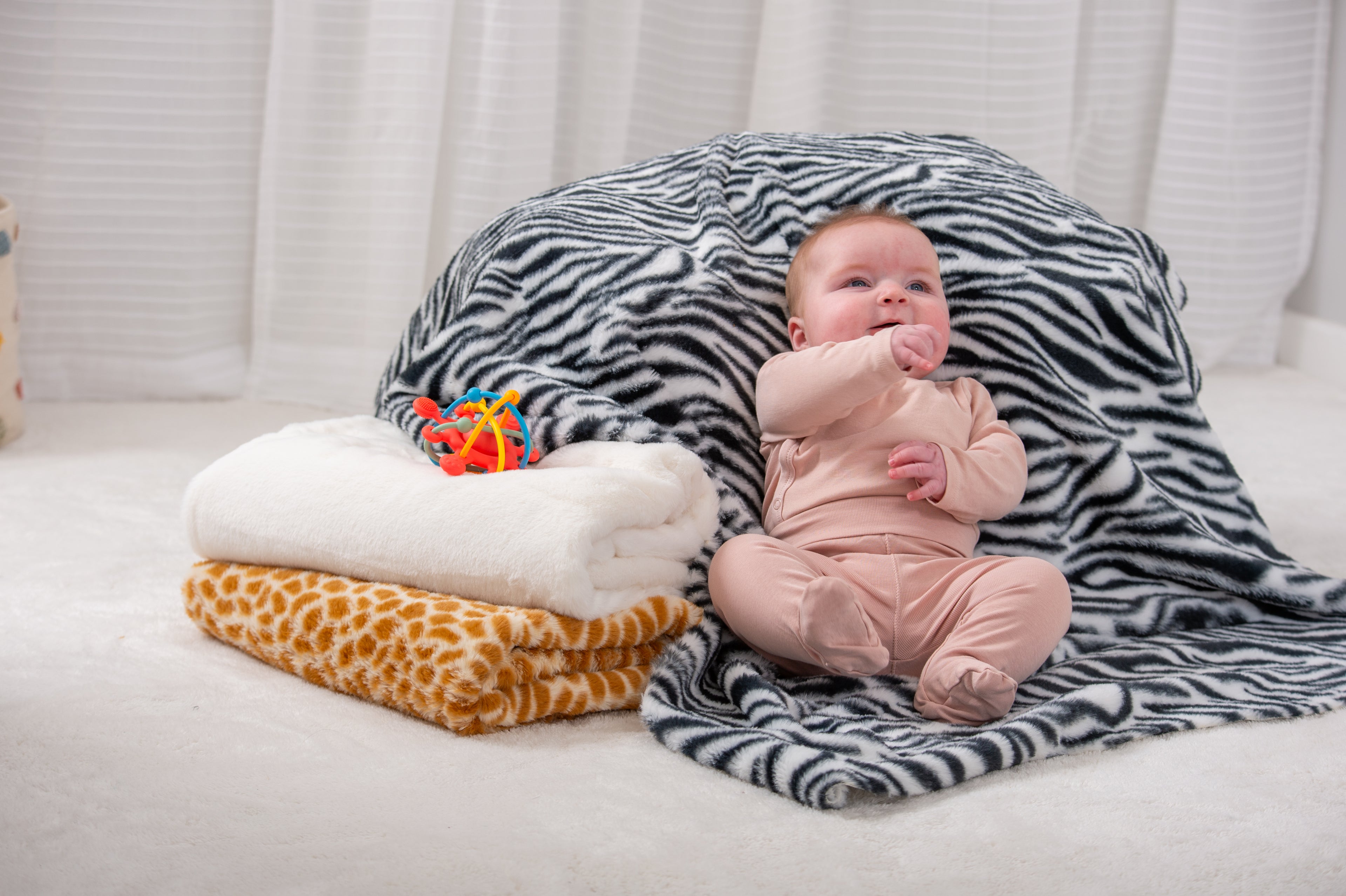 Furry animal print blanket set with black zebra and orange giraffe patterns over white plush